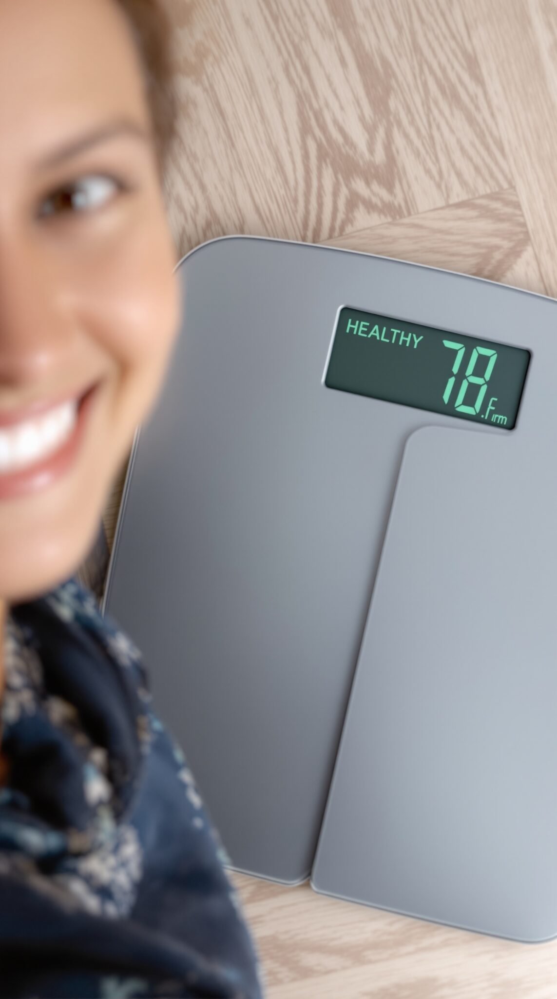 A woman happily looking at a scale with the reading 'HEALTHY 78.6'.